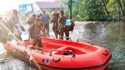 Sigap Hadapi Banjir Rob, Babinsa Kelurahan Bontang Kuala Serma Purnomo Bantu Warga dan Pelajar Melintasi Genangan Air